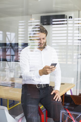 Fototapeta premium Happy young man using his smart phone at office