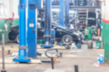 Car technician repairing car in workshop service station blur background.