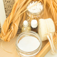 Eco accessories for body care and spa - bast, loofah, wooden cotton swabs in a glass jar, essential and aroma oil on a wooden tray. Zero waste concept