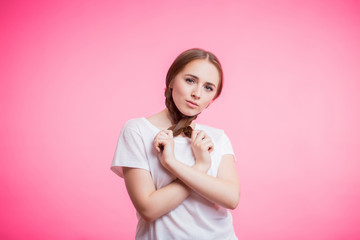 Beautiful portrait of young student girl with pigtails and white t-shirt on pink background