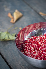 Fresh pomegranate seeds in metal bowl on wooden table