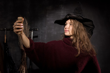 Young lady in witch costume taking selfie