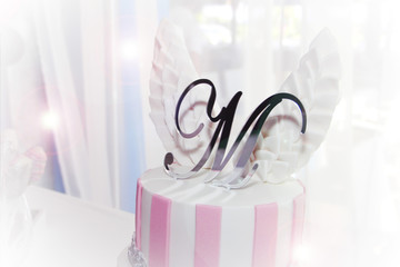 a birthday cake with a white and pink cream and white wings and the letter M
