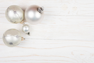 Christmas balls of a silver color on a white wooden background (copy space for your text, top view) as a New Year or Christmas background
