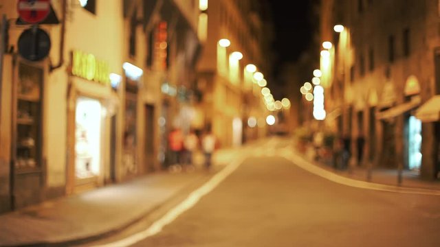 Out of focus background plate of urban European street at night with people