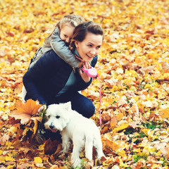 Mother and daughter on autumn walk with dog. Happy loving family having fun. Small white dog and family enjoying together outdoors. Family, pet and lifestyle concept.