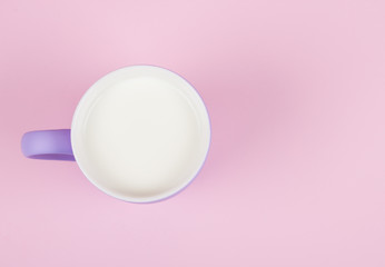 Cup of milk against a pastel pink background, copy space for your text (top view, minimal concept)