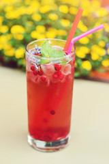 Cold drink with cowberry and lavender on table, outdoors. Summer cocktail of cowberry with ice and fresh lavender. Red freshment drink with cowberry at cafe terrace. Summer cold drink outdoor.