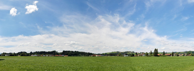Panoramic view of an alpine village, south Bavaria. Beautiful peaceful landscape, summertime, wide bavarian sky with some white clouds, green meadows and tiny houses.