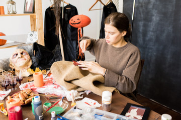Busy woman adding colorful leaves while sewing burlap