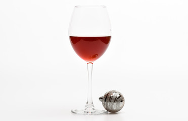 New year party concept. Glass with wine and christmas decoration. Wineglass with red liquid or wine and christmas ball ornament isolated on white background. Winter celebration with alcohol drink