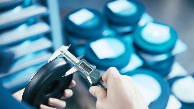 Industry line quality check with measuring tool 4K. Over shoulder view of rubber product and measuring tool in focus making a quality check of an industrial process.