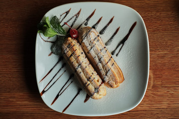 Two sweet french eclairs on plate. Breakfast in cafe.