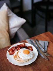 Tasty breakfast with pancakes, fried egg and bacon, top view