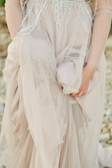 Fototapeta na wymiar Closeup of bride's hands on wedding dress outside