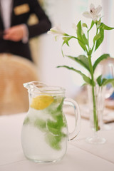 Glass jug of cold lemonade on a light background cafe. Pitcher lemon water with mint. Cold lemonade box