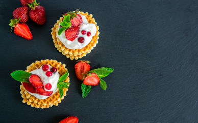 Waffles with whipped cream and strawberries on slate board