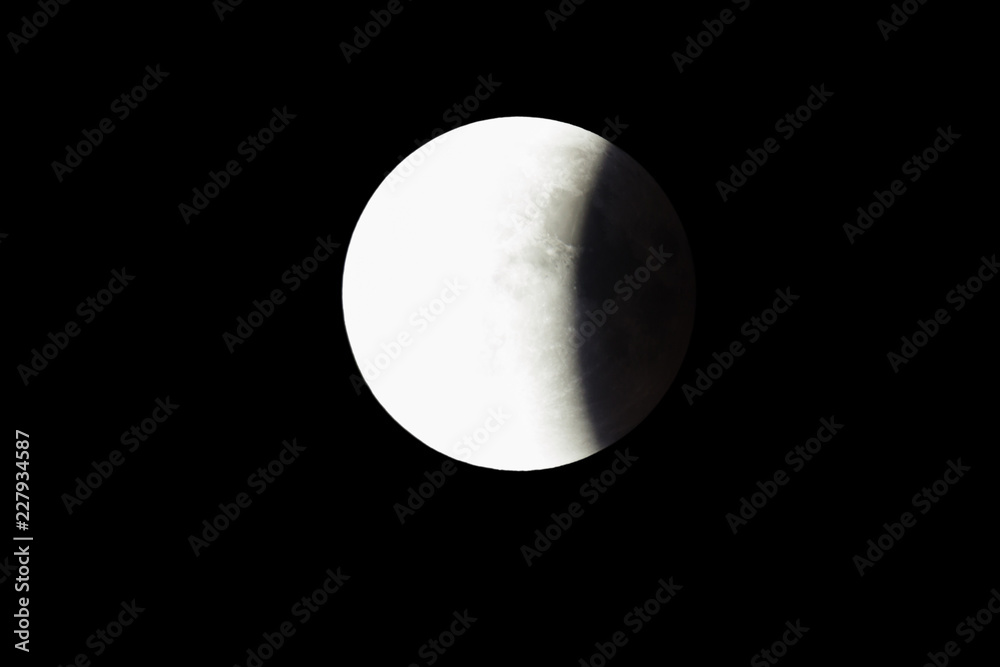 Wall mural super bloody moon, full eclipse last phase against black sky background, one third of the moon surfa