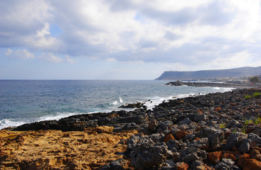 breaking waves at the red rocky coast of Sissi on Crete in Greece
