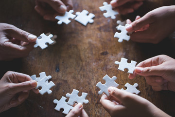 Hands of diverse people assembling jigsaw puzzle, Youth team put pieces together searching for right match, help support in teamwork to find common solution concept, top close up view