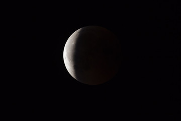 Super Bloody Moon, full eclipse end phase against black sky background, three-quarters of the Moon surface covered by Earth's shadow