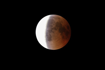 Super Bloody Moon, full eclipse end phase against black sky background, three-quarters of the Moon surface covered by Earth's shadow