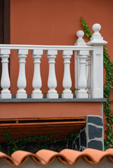 White balustrade of porch on bright red-orange wall background.