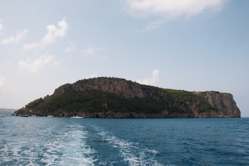 Fototapeta premium Isola in mezzo al mare e scia della barca. Calabria, Sud Italia.