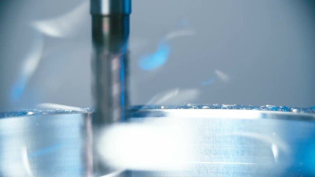 Making an iron product with milling machine close-up 4K. Long shot tracking a drill scraping away parts of the iron in slow motion. Industrial process.