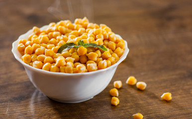 closeup of a bowl with boiled chickpeas on wooden table background