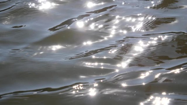 Water ripples in slow motion with sun reflecting in lake surface