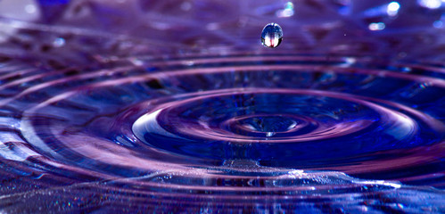 Wassertropfen in blaues Wasser mit Kugel