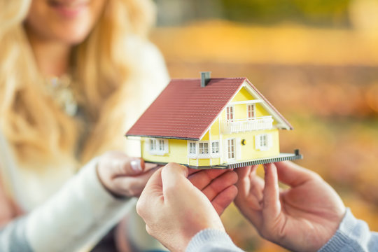 Young loving couple holding small model house.