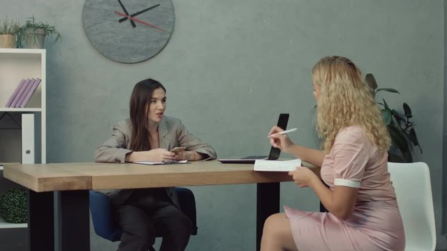 Confident businesswoman planning schedule and giving tasks to her assistant in office. Successful female entrepreneur giving instruction to her female assitant at workplace in modern office.