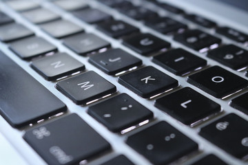 Primo piano di una tastiera di computer, messa a fuoco su lettere M,K,O, vista dall’alto