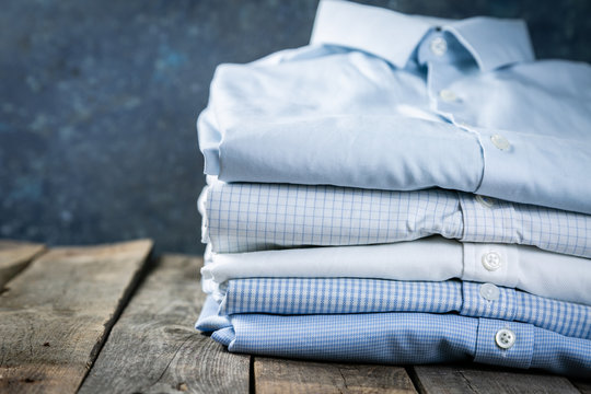 Stack of male folded shirts on rustic background, copy space