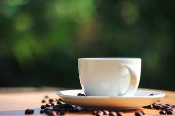 Coffee cup in the morning wooden table and green nature background.