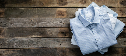 Stack of male folded shirts on rustic background, top view