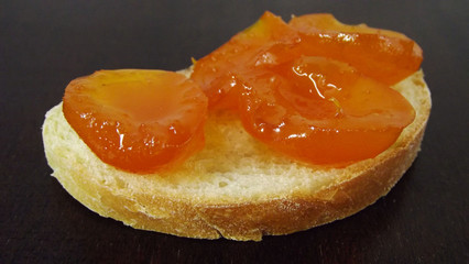 Bread and delicious jam of ripe apricots on the table.