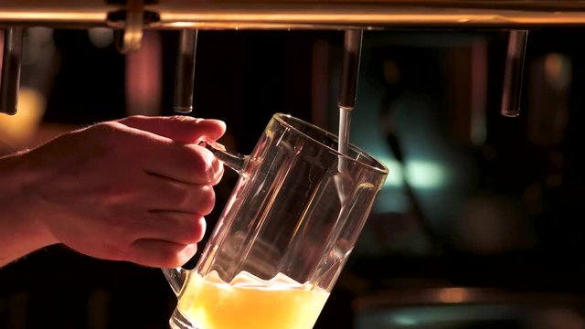Close-up filling beer from beer pump. Barman hand pouring a lager beer in a glass.