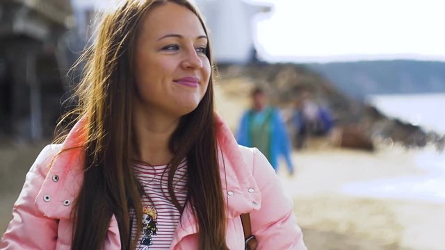 Close up portrait of Young Woman smiling with brown hair blowing in wind looking arround