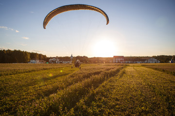 Paratrayke flight, paraglider in the sky at sunset. The wing of a parachute with a paraglider cabin flies across the sky in the setting sun