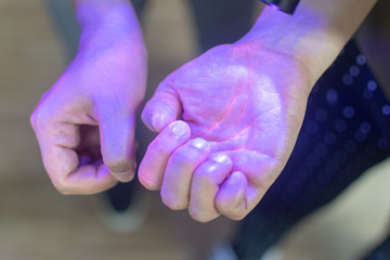 Hands under black UV light to detect glow in the dark germs around nails and fingerprint as visual...