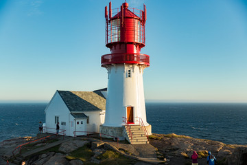 Old Lighthouse Lindesnes fyr is a coastal lighthouse located on the southernmost point of continental Norway in Lindesnes, South Cape. Serene Scandinavian landscape, Rocky Mountains, fjord, sunset sky - obrazy, fototapety, plakaty
