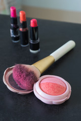 Cheek brush and pink powder on blurred lip stick background,
