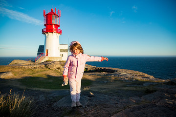 Little girl stands on rocky northern seashore, exploring the coastal rocks. Travel and enjoy a...