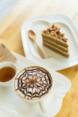 hot coffee late in white glass on wooden table, blurred cake and wooden spoon,