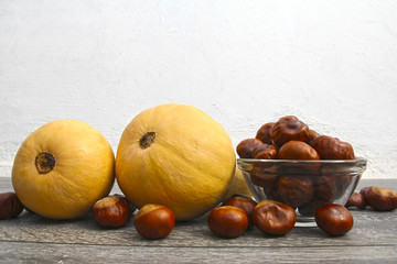 Ripe pumpkins and chestnuts on a light background