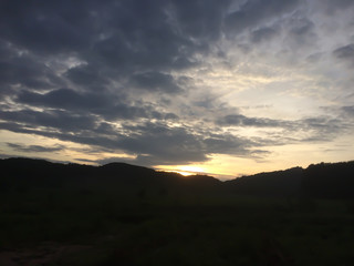 Silhouette of mountain under evening sky with dark clouds and sunsets.