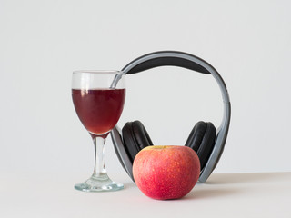 wine apple in glass with black hreadphone on white background,